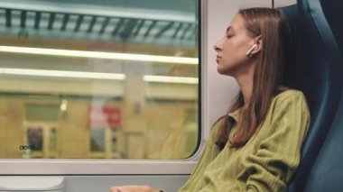 Trenle seyahat ederken pencereden dışarı bakan genç bir kadın.