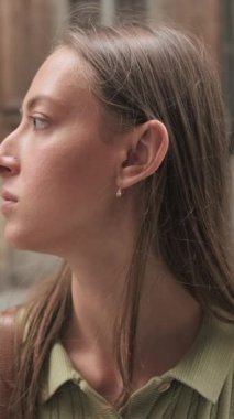 Yakın plan, gülümseyen genç bir kadın başını çeviriyor ve Avrupa 'nın caddesindeki kameraya bakıyor.