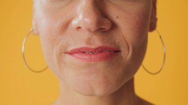 Sarı arka planda izole edilmiş kadının dudaklarının detaylı yakın plan çekimi.