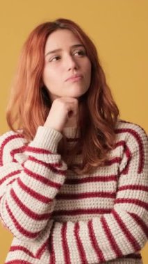 Dalgın kız sarı arka planda stüdyoda seçim yapıyor.