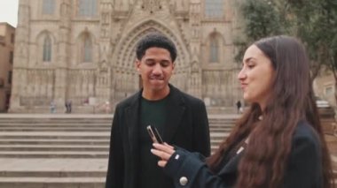 Turist çift katedralin önünde akıllı telefonlarıyla selfie çekiyor..
