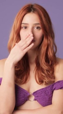 Şaşkın, tatminsiz kız mor arka planda hayal kırıklığına uğramış görünüyor.