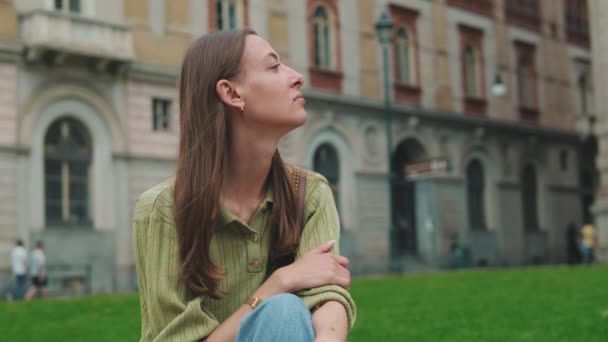 古い街の背景に座っている若い幸せな女性 — ストック動画