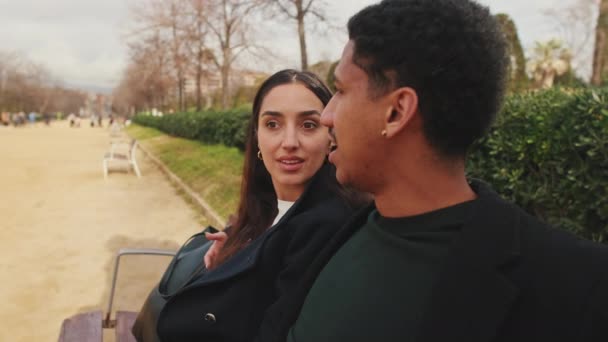 快乐的年轻夫妇在公园的长椅上聊天 — 图库视频影像