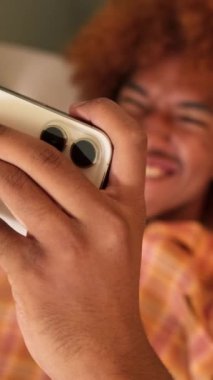 Evdeki cep telefonuyla video oyunu oynayan adamın ellerini yakın plan çek.