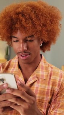 Oturma odasında cep telefonu kullanan mutlu adam.