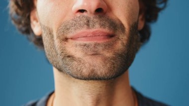 Stüdyoda mavi arka planda bir adamın ağzının detaylı yakın plan çekimi.