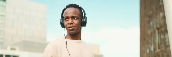 Joven Estudiante Africano Sentado Fuera Universidad Usando Auriculares Usando Teléfono — Foto de Stock