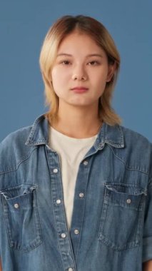 Kafası karışmış genç bir kadın ellerini kaldırıyor. Mavi arka planda yalnız olduğundan emin değilim.