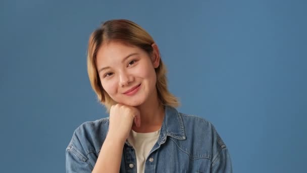 Gülümseyen Genç Kadın Mavi Arka Planda Izole Edilmiş Kameraya Bakıyor — Stok video