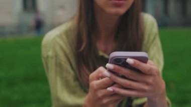 Kadının elleri cep telefonu tutarken yakın plan, kameranın odak noktası yüze geçiyor