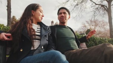Parktaki bankta sohbet eden mutlu genç çift.