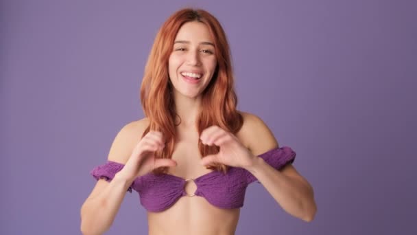 微笑的女孩在紫色背景上表现出心形 — 图库视频影像