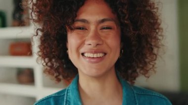 Evde kameraya bakan gülen genç bir kadının portresi.