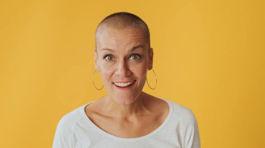 Yakından, şok olmuş genç, tüysüz bir kadın, büyük gözleriyle kameraya bakıyor, diyor ki vay, sarı arka planda izole edilmiş, stüdyoda