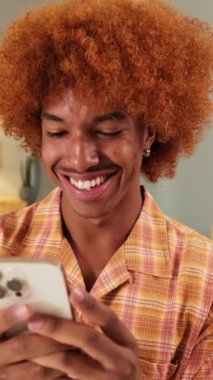 Oturma odasında cep telefonu kullanan mutlu adam.