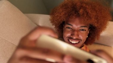 Yakın plan, adam oturma odasında kanepede yatarken video oyunu oynuyor.