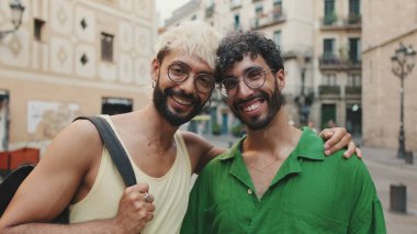 Homoseksüel çift karşılarında dikilip eski şehrin sokaklarında kameralara bakıyor.
