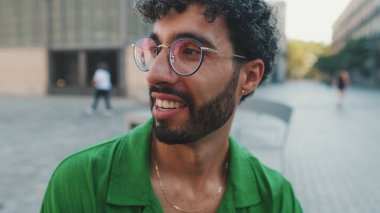 Sakallı, yeşil gömlekli hoş esmer adam, biriyle konuşuyor.