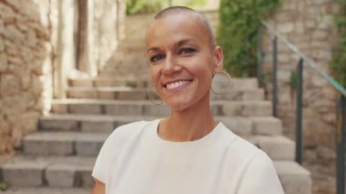 Çok kısa saçlı gülümseyen bir kadının yakın plan portresi.