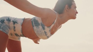 Zarif bayan atlet, yazın deniz kenarında ısınarak ileri doğru virajlar alıyor.