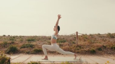 Yoga yapan ve dışarıda egzersiz yapan genç bir kadının portresi, yoga dersleri için video ve asanas rehberi.