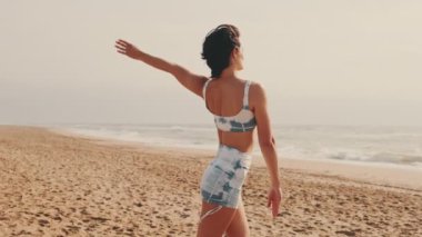 Sahilde yoga yapan bir kızın yan görüntüsü, deniz kenarında yoga dersi, zarif bayan atlet hareketin esnekliğini gösteriyor