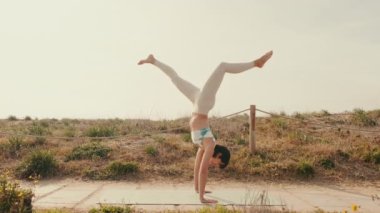 Açık renkli spor giyimli bir kız yazın yoga ve spor yapıyor.