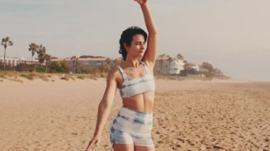 Sahilde yoga yapan bir kız, deniz kenarında yoga dersi, zarif bayan atlet hareketin esnekliğini gösteriyor.