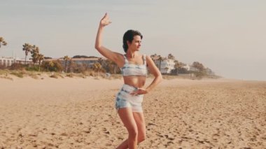 Sahilde yoga yapan bir kız, zarif bayan atlet hareketin esnekliğini gösteriyor.