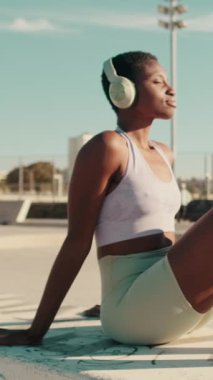 Kulaklıklı kız sporcunun kaykay parkında takılırken görüntüsü.