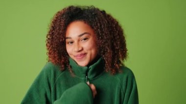 Şirin bir kız yeşil ekran arka planında sweatshirt giyiyor.