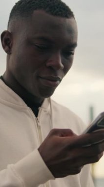 Telefon ekranına bakarak akıllı telefon kullanan genç bir adamın yakın çekimi.