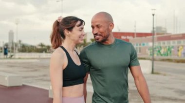 Deniz kenarında yürüyen ve kucaklaşan sportif bir çift, bir erkekle bir kadın arasındaki yakın diyalog.