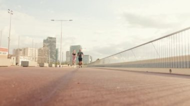 Genç, neşeli, aktif bir çift güzel bir deniz kenarında birlikte koşuyor. Temel odak