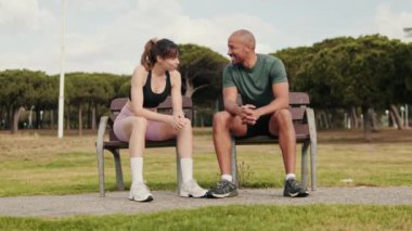 Genç ve güzel atletik çift yazın parkta dinleniyor ve sohbet ediyorlar.