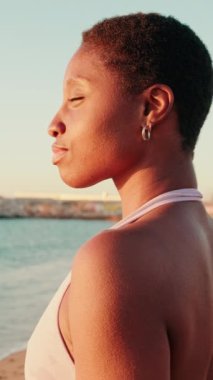 Şafakta deniz kenarında meditasyon yapan bir kızın dikey videosu.