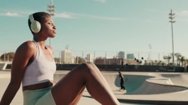 Kaykay parkında takılan kulaklıklı kız sporcunun yakın görüntüsü.