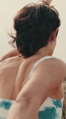 Spor kıyafetleriyle dışarıda yoga yapan bir kızın arka görüntüsü.