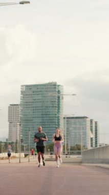 Sahilde birlikte koşan genç aktif çiftin panorama manzarası.