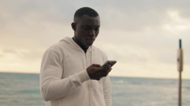 Sokaktaki akıllı telefon ekranına bakıp arkadaşlarıyla sohbet eden, sosyal ağları kaydıran bir adamın yan görüntüsü.