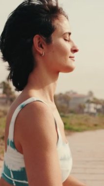 Bir kız kumsalda meditasyon yapıyor. Kumun üzerinde duruyor. Yoga dersleri ve Asana Rehberi videosu..