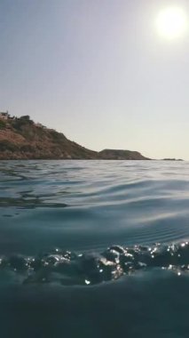 Kıyı kayaları olan su yüzeyi, alçak açılı çekim, arka plan ışığı, deniz manzarası