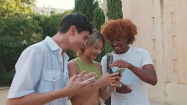Parkta yürüyen ve akıllı telefon kullanan gençlerin yan görüntüsü