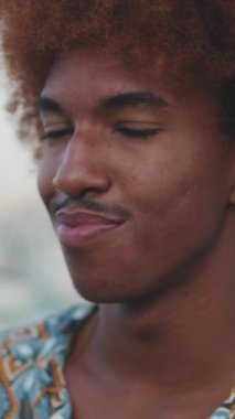 Mutlu kıvırcık saçlı adamın yakın plan çekimleri bir yatın ve palmiye ağaçlarının arka planında rahatlarken, zoom