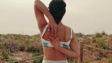 Dışarıda yoga yapan, egzersiz yapan genç bir kadının arka görüntüsü.