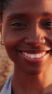 Gün doğumunda sahilde, kameraya bakıp gülümseyen çekici bir kızın portresi.