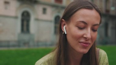 Kablosuz kulaklıkla müzik dinleyen gülümseyen kadının yakın çekimi.
