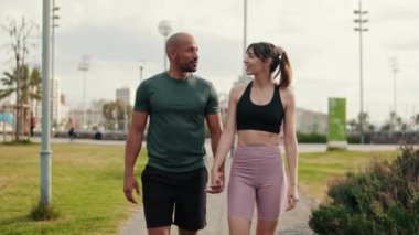 Parkta el ele tutuşan genç atletik çift