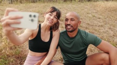 Birbirlerine aşık sporcu bir çift dışarıda akıllı telefonlar kullanıyor, selfie çekiyorlar.